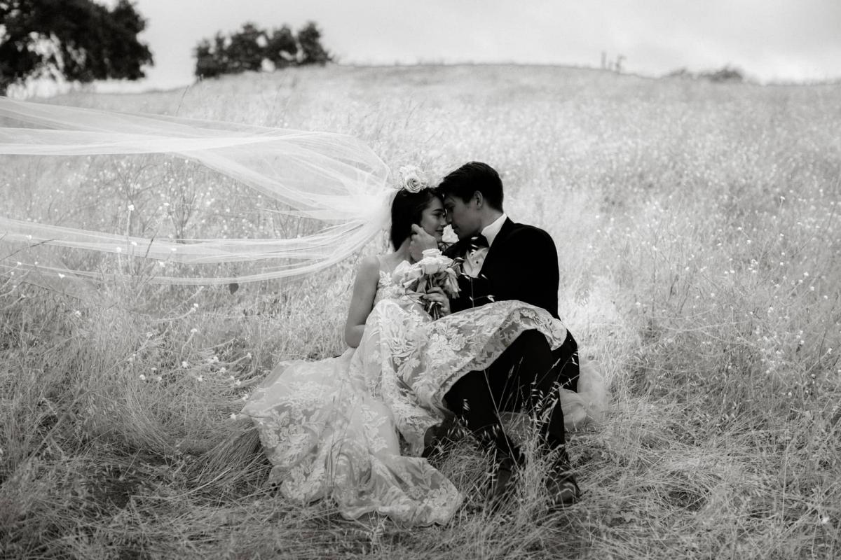 Black & White of Bride & Groom Sitting in Field for Mika & James's Wedding
