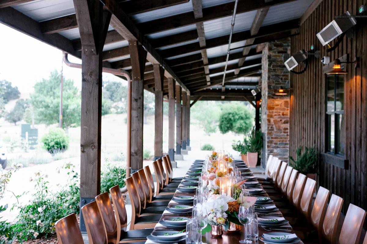 End View of Long Reception Table with Candles on Veranda Behind Hills for Mika & James's Wedding