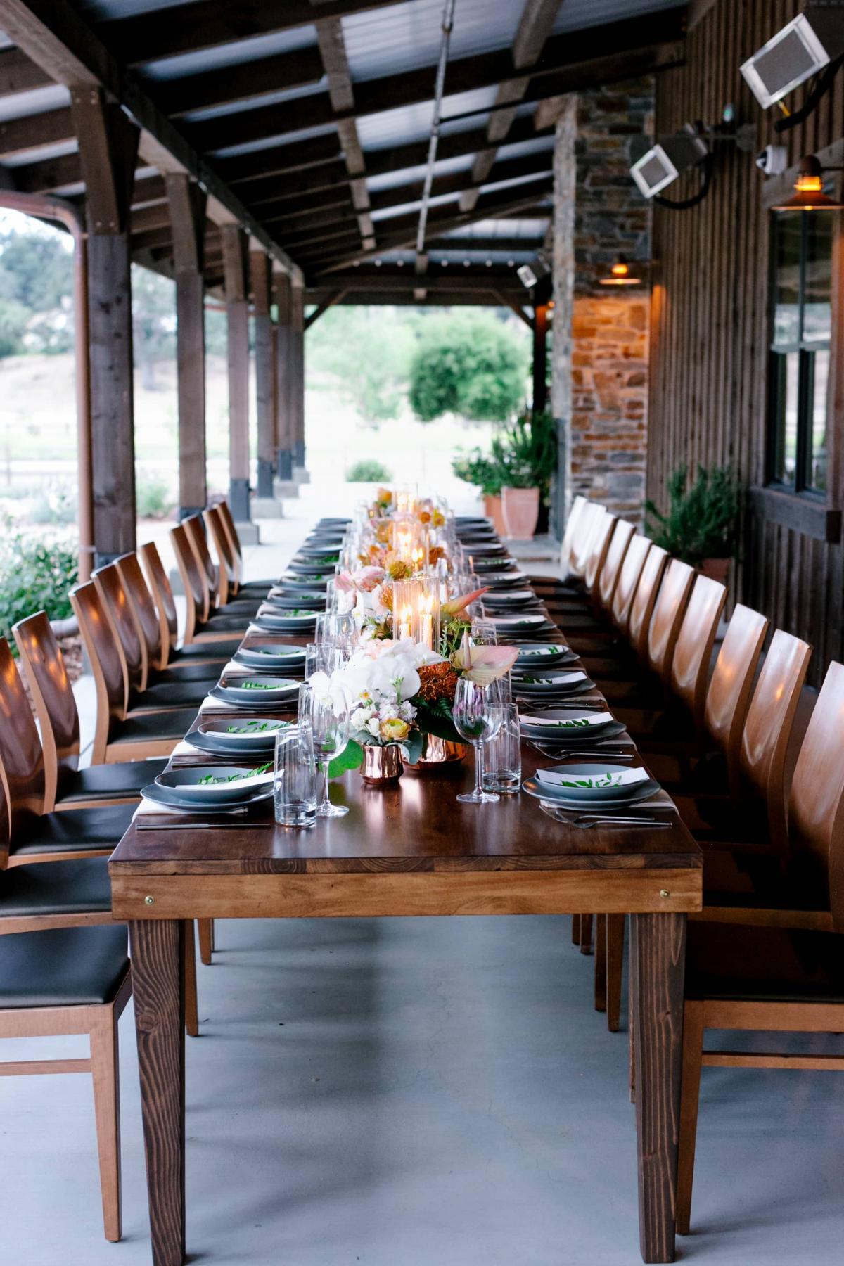 Tall View of Long Reception Table with Candles on Veranda Behind Hills for Mika & James's Wedding