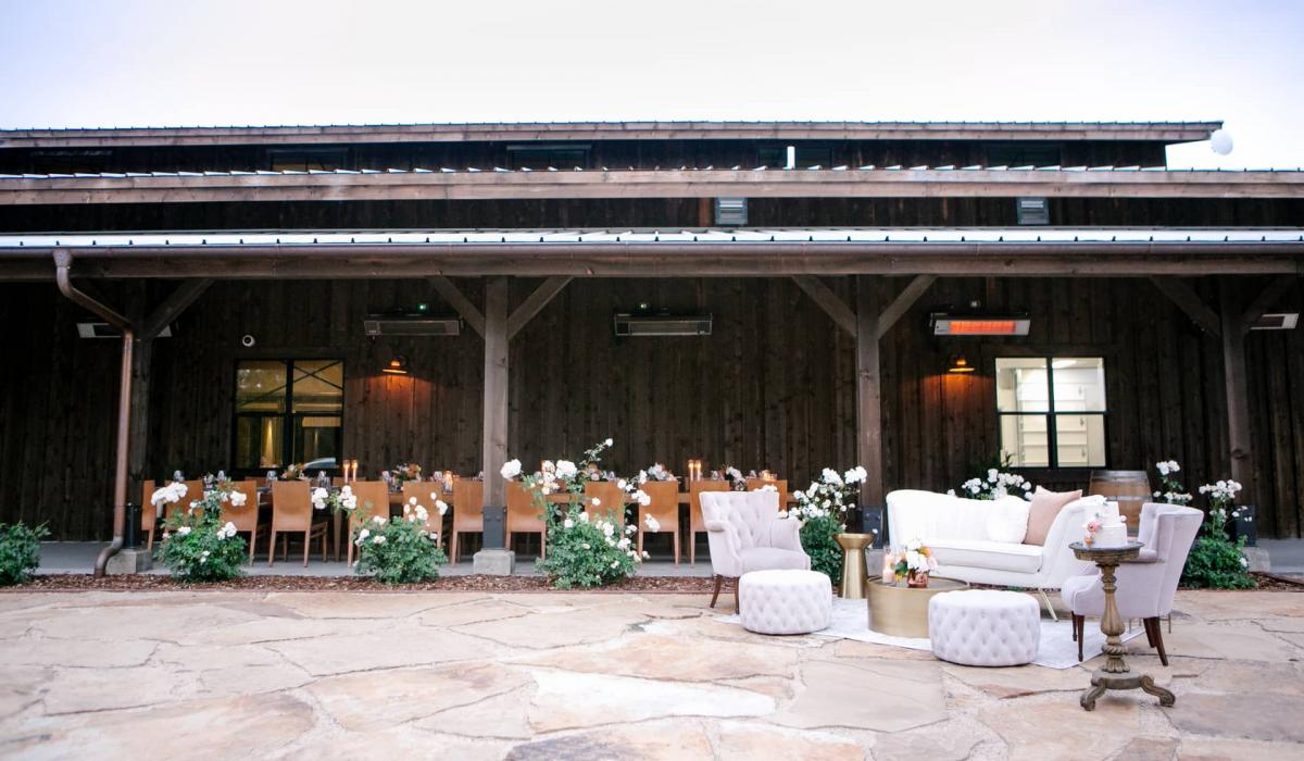 Wide View Outdoor Setting with Couch, 2 Chairs, Coffee Table and Poofs with Reception Table Behind for Mika & James's Wedding
