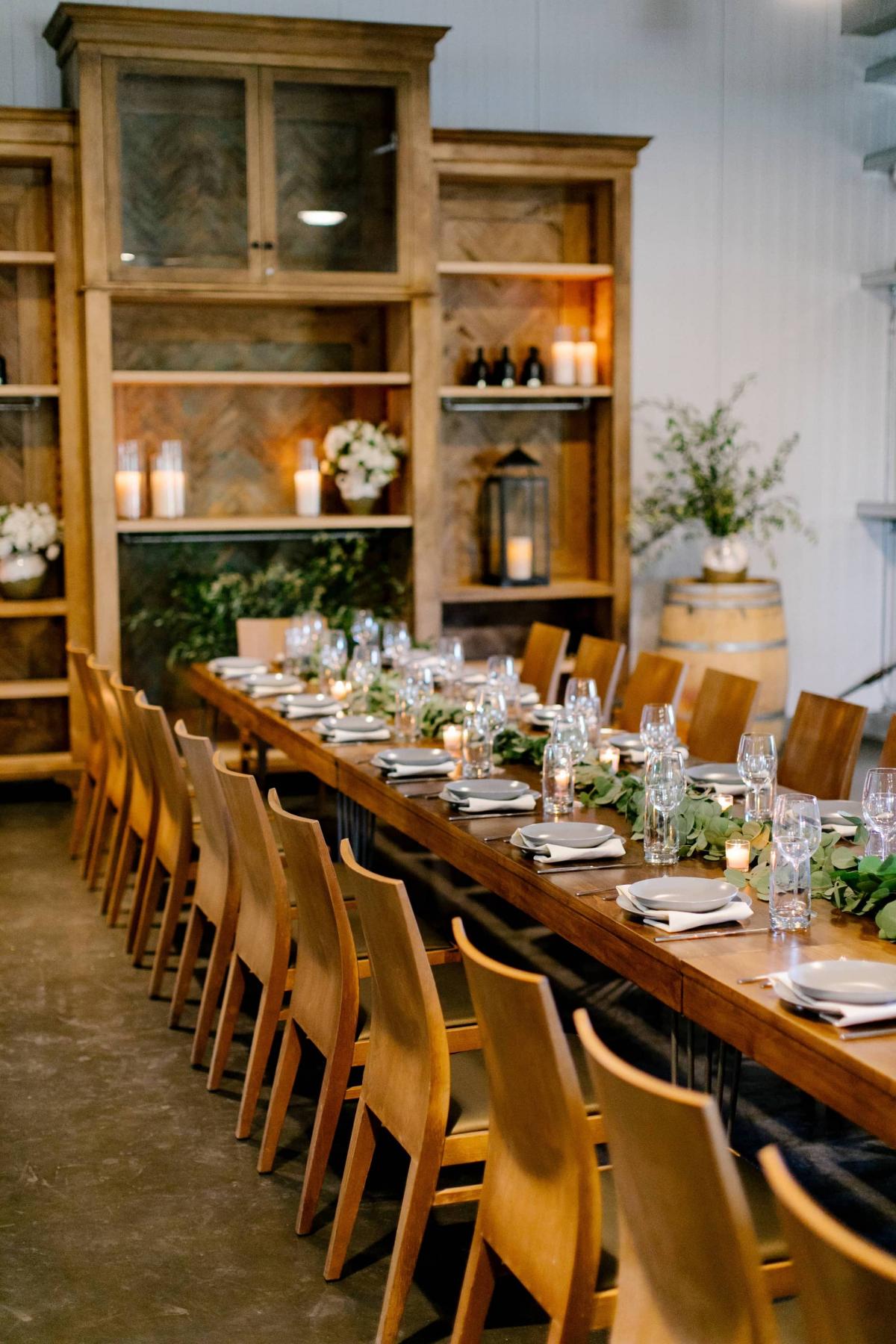 Left Angle of Long Reception Table, Chairs, Candles with Bookcase Behind at Petros Winery