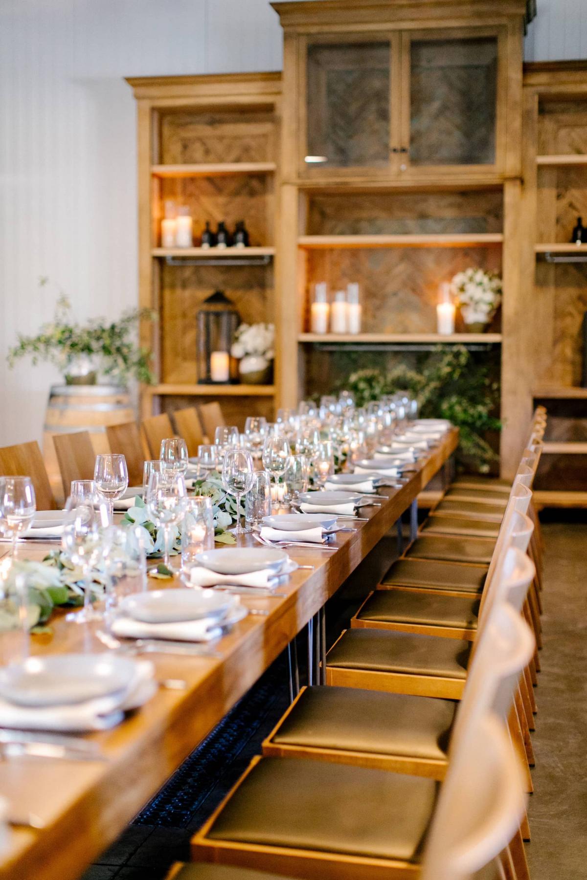 Right Angle of Long Reception Table, Gold Chairs, Candles with Bookcase Behind at Petros Winery