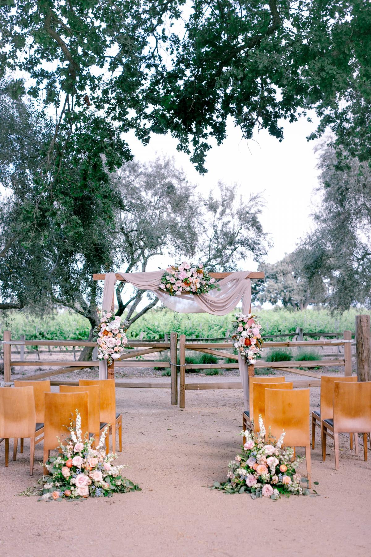 Outdoor Reception Area with Chairs, Flower Arrangements & Archway for Mika & James's Wedding